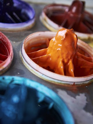 Close-up of paint manufacturing equipment with bright red, orange, blue and purple liquid pigments.