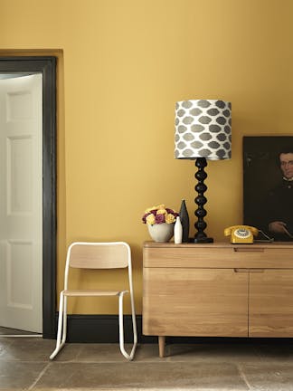 Hallway painted in mustard yellow (Yellow-Pink) with a wooden side table and chair.