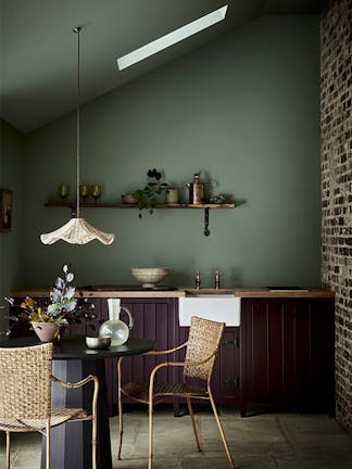 Kitchen with a soft green back wall (Windmill Lane) and aubergine purple (Cordoba) kitchen cabinets with a table and chairs.