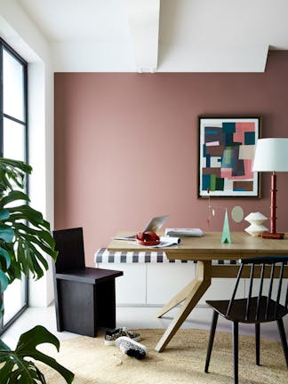 Home office with a mud red Nether Red painted wall, abstract framed art and a lamp.