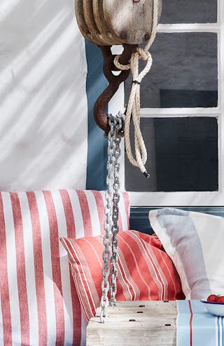 Yard with door and shutters painted in deep blue (Hicks' Blue) and a white wall, with a seating area and striped cushions.