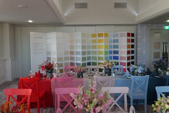 Long tables with Little Greene paint tins holding flowers, multi-colored tablecloths and a Colorcard in the background.