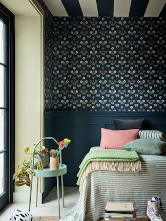 Bedroom featuring dark blue small print wallpaper (Burges Butterfly - Hicks' Blue) with a bed next to a large window and sidetable.