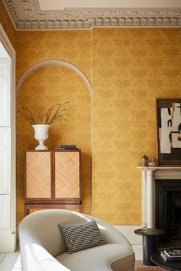 Living room with yellow floral wallpaper (Dahlia Scroll - Giallo) with a chair, cabinet and fireplace,