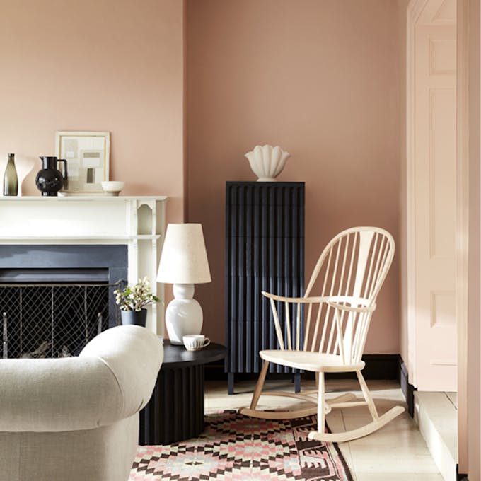 Pale pink living room in varying shades of Masquerade, alongside a rocking chair, sofa and Aztec rug.