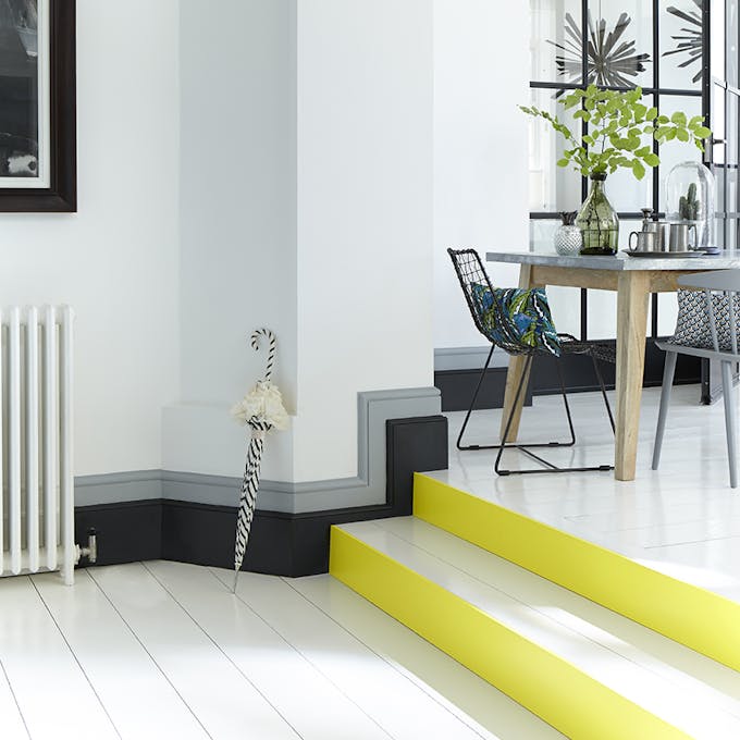 White stairs in a hallway with bright yellow (Trumpet) contrasting stair risers and a black and grey baseboard.