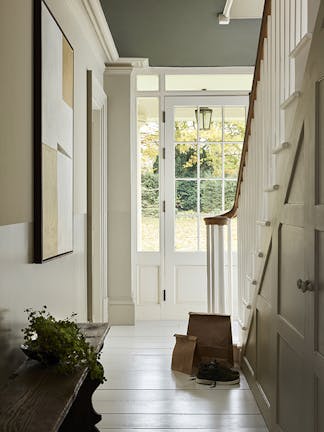 Hallway painted in four graduating shades of neutral 'Portland Stone' with a white wooden floor and a staircase to the right, looking out to a garden.