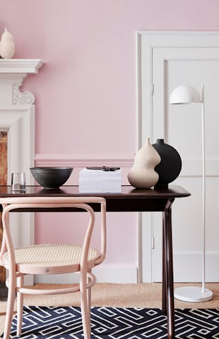 Light pink walls alongside a white fireplace surround and white doors.