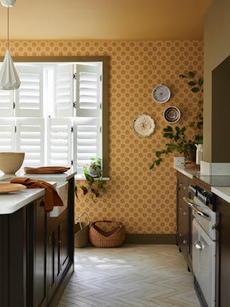 Kitchen space featuring golden yellow small print floral wallpaper (Ditsy Block - Bombolone) with a large window and dark brown cabinets.