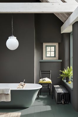 Bathroom painted in dark grey 'Vulcan' with contrasting grey, green (Livid) details with a bathtub, chair and window.