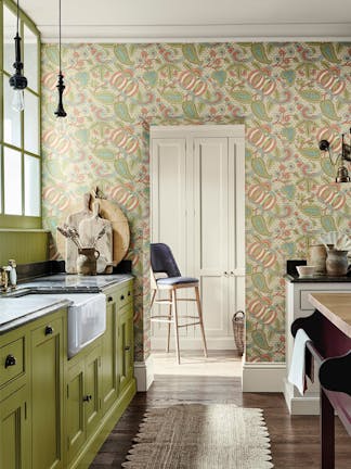 Kitchen with bright green cabinets (Citrine) and a paisley wallpaper (Pomegranate - Bazaar) with a wooden floor and rug.