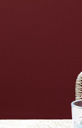 Close-up of a deep red wall with a glass green jug and cup in the forefront.