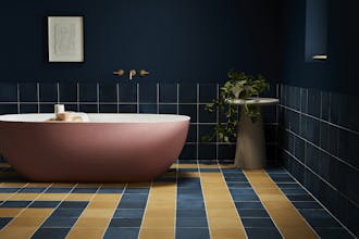 Deep blue (Royal Navy) bathroom with constrasting yellow and blue tiles and a large pink bathtub.