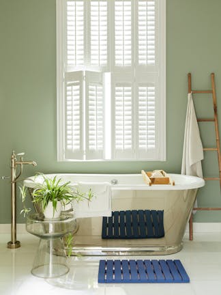 Bathroom painted in grey/ green 'Boringdon Green' with a silver bathtub under a large window.