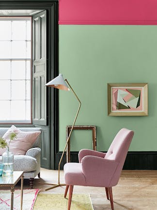 Living room painted in light green 'Pea Green' with a bright pink contrast stripe and pale pink chair.