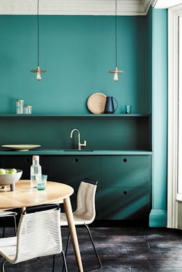 Kitchen painted in blue green (Tea with Florence) and dark green (Harley Green) with a round wooden table and chairs.