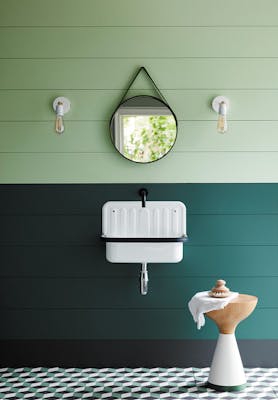 Paneled bathroom with the upper wall painted in Aquamarine and lower wall in dark green with a white sink and round mirror.