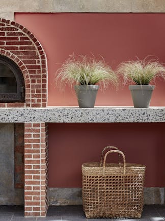 Outdoor kitchen painted in deep terracotta red 'Tuscan Red' with brickwork, plants and a basket.