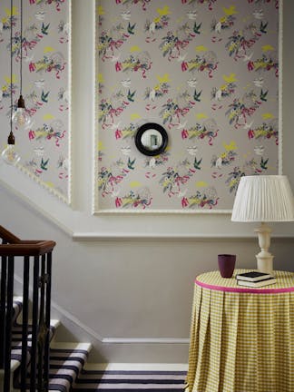 Bottom of stairs with grey bird print wallpaper (Voliéres - French Grey) and a small table with yellow gingham tablecloth.