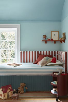 Children's bedroom painted in three shades of light blue ('Brighton', 'Sky Blue' and 'Etruria') with a striped blue, red and white comforter on the bed and toys on the floor.