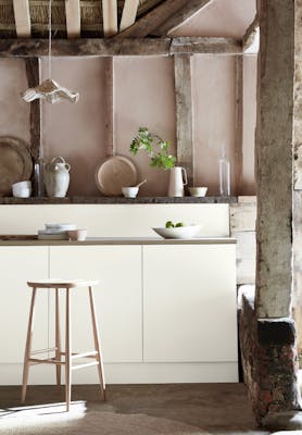 Kitchen space with wooden pillars and ceiling with off white (Flint) units and a wooden bench.