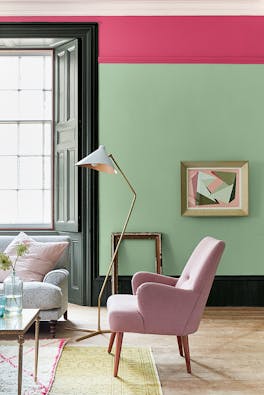 Living room painted in light green 'Pea Green' with a bright pink contrast stripe and pale pink chair.