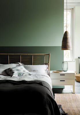 Bedroom with the upper wall painted in Aquamarine and the lower wall in Aquamarine - Pale with a double bed and side table.