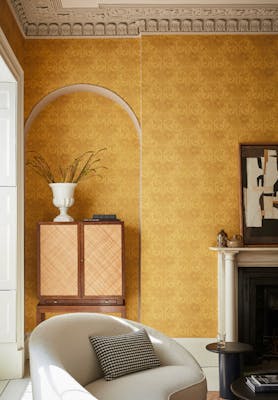 Living room with yellow floral wallpaper (Dahlia Scroll - Giallo) with a chair, cabinet and fireplace,