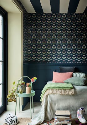 Bedroom featuring dark blue small print wallpaper (Burges Butterfly - Hicks' Blue) with a bed next to a large window and sidetable.