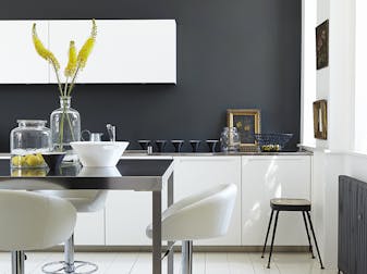 Rich black (Lamp Black) kitchen with bright white units and stools next to a black table.