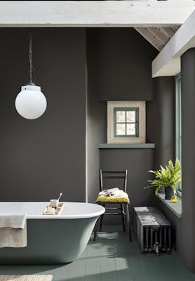 Bathroom painted in dark grey 'Vulcan' with contrasting grey, green (Livid) details with a bathtub, chair and window.