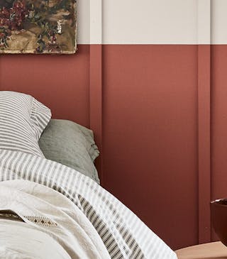 Bedroom with a light grey (French Grey) upper wall and a terracotta red 'Tuscan Red' lower wall behind a bed.