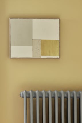 Landing decorated with Light Gold walls, grey radiator and hanging artwork.