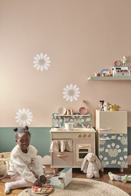 Playroom with pale pink (Masquerade) walls with a child playing with a toy cooker.