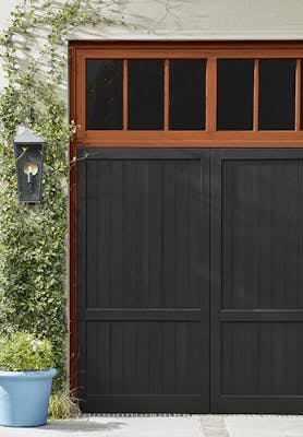 Panelled exterior doors painted in deep black 'Jack Black' with burnt orange (Heat) windows above and greenery on the walls.