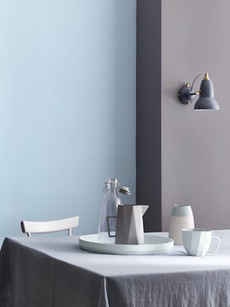 Dining room painted half in blue grey (Arquerite) and half in light blue (Pale Wedgwood) with a table and crockery on top.