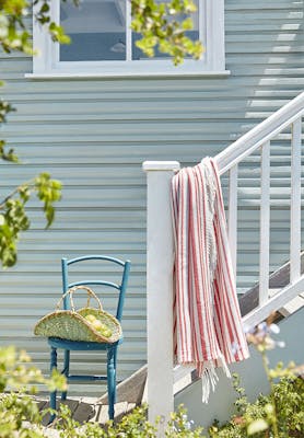 Outdoor cladded wall painted in grey blue shade 'Celestial Blue' with a bright blue chair at the bottom of some outside steps.