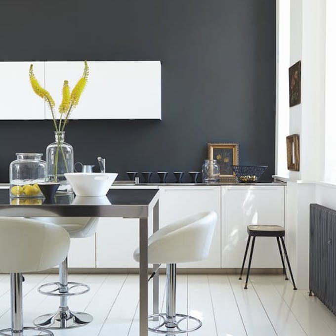 Rich black (Lamp Black) kitchen with bright white units and stools next to a black table.