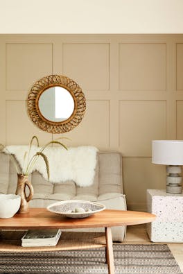 Paneled living space painted in warm neutral 'Travertine' with two sofas and a wooden coffee table.