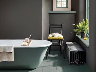 Bathroom painted in dark grey 'Vulcan' with contrasting grey, green (Livid) details with a bathtub, chair and window.