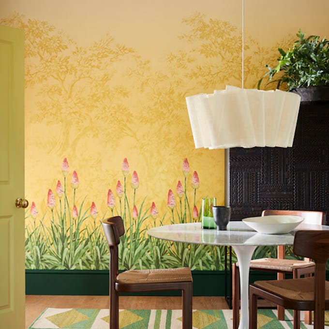 Dining room with yellow mural wallpaper (Upper Brook Street - Soleil) and a dining room table with wooden chairs.