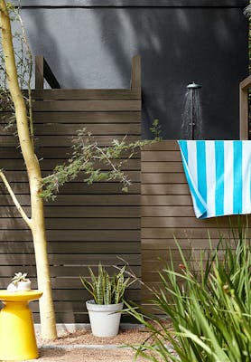 Outside shower area with a paneled fence with a rich black wall (Lamp Black), surrounded by plants.