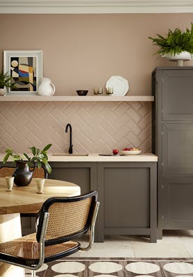 Kitchen painted in muted pink shade 'Mochi' with contrasting neutral brown 'Attic II' units with a dining room table and chair.