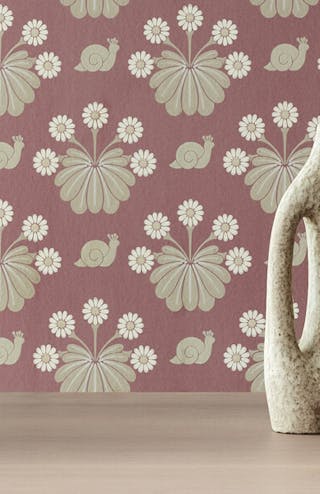 Close-up of Burges Snail - Rosie pink wallpaper featuring flowers and snails alongside a table with vases.