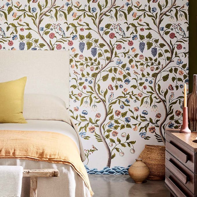 Bedroom featuring white wallpaper comprised of trees in different colors.