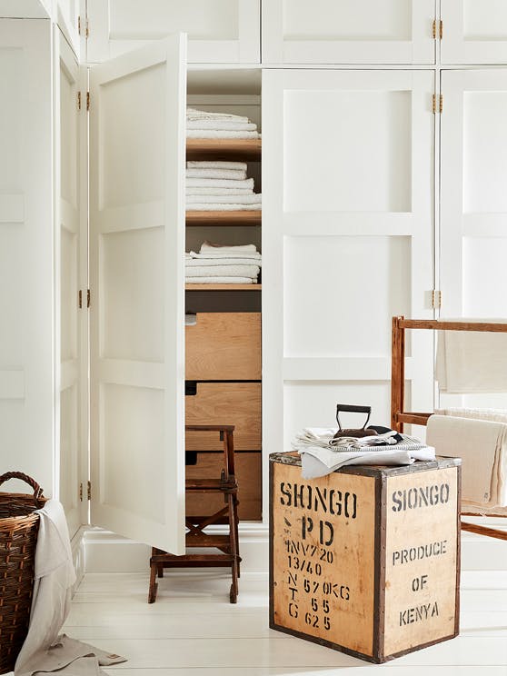 Laundry room drenched in off white 'Linen Wash' with the closet door open showing wooden drawers and folded laundry.