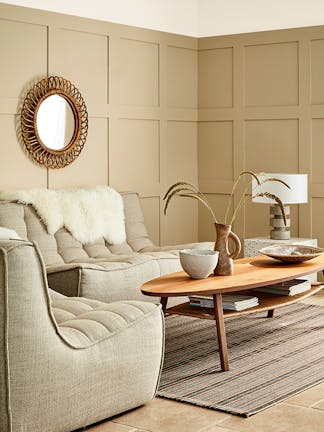 Paneled living space painted in warm neutral 'Travertine' with two sofas and a wooden coffee table.