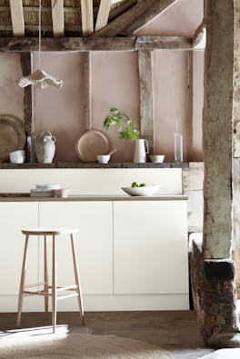 Kitchen space with wooden pillars and ceiling with off white (Flint) units and a wooden bench.