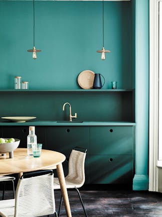 Kitchen painted in blue green (Tea with Florence) and dark green (Harley Green) with a round wooden table and chairs.