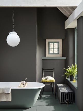 Bathroom painted in dark grey 'Vulcan' with contrasting grey, green (Livid) details with a bathtub, chair and window.